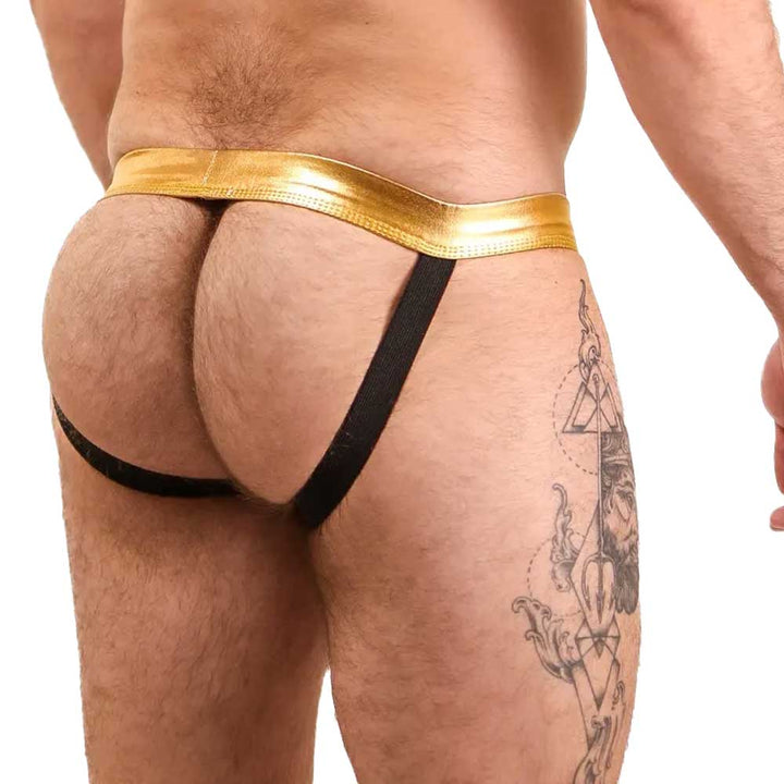 Gold thong worn by a person with tattoos on a white background. Bold Envy Gay Mens Jock Strap Sexy Apparel